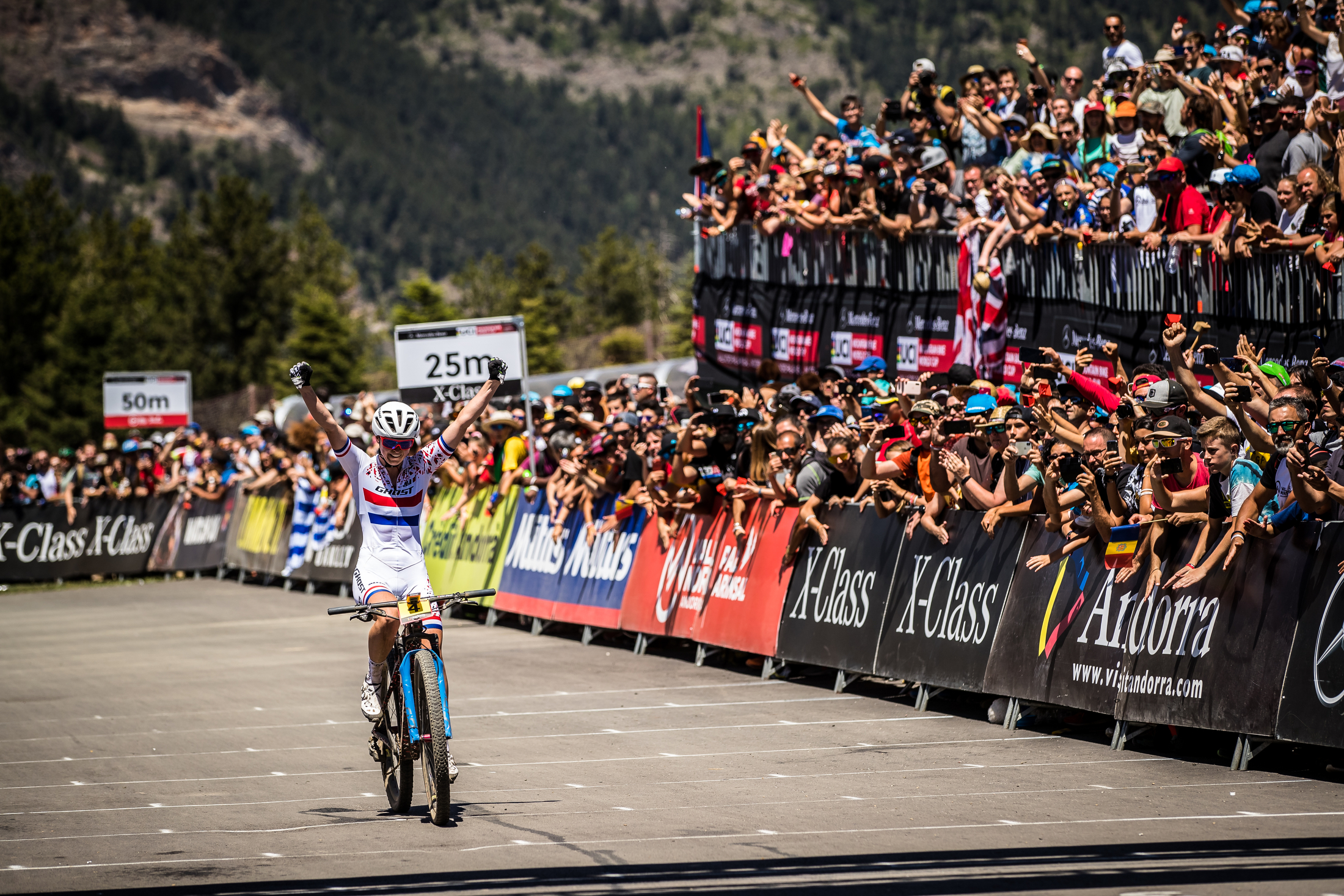 Anne Terpstra rides across the finish line, with fists in the air.